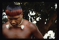 Suptó, who is a leader of the Pimentel Barbosa community, sings one of his dreamed songs. His earplugs act as “antennae,” enabling him to tune in to the immortals in his dreams. His forehead and hair are painted with highly valued red urucum paint. Photo by Laura Graham.