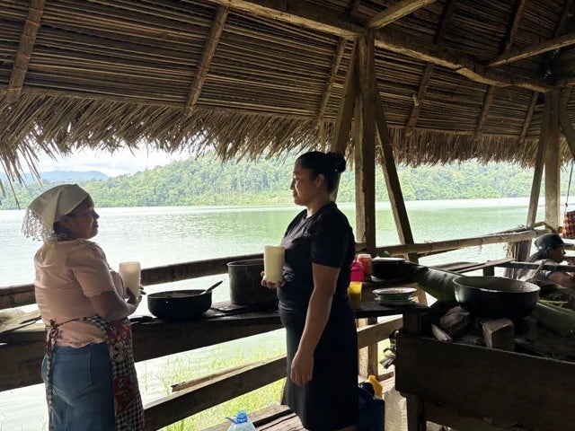 Two people in an open wooden shelter overlooking the water.
